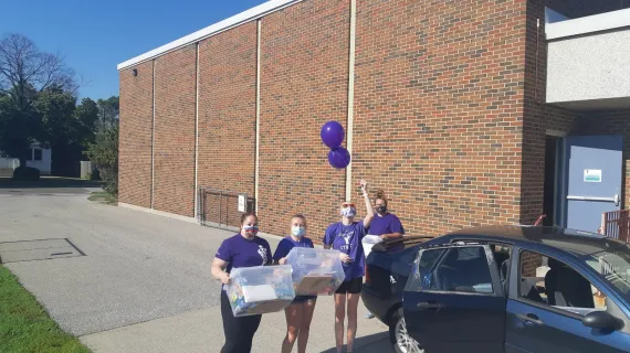 Four "Purple Shirt" camp staff pack up camp kits to deliver to families outside the YLCC.