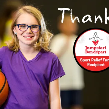 A young girl in a purple shirt smiles and holds a basketball.